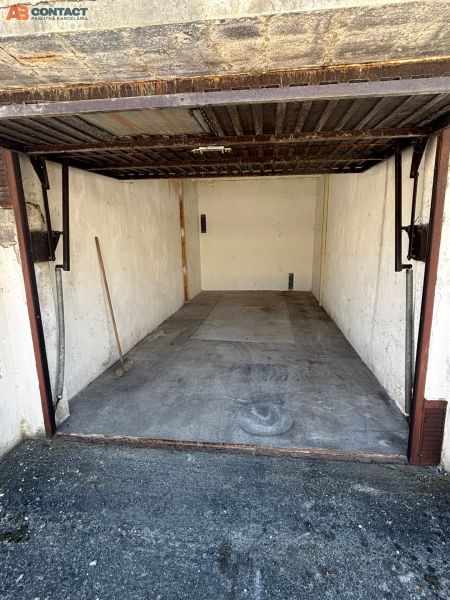 An open garage on Dopravná Street in Piešťany with a concrete floor and a broom.