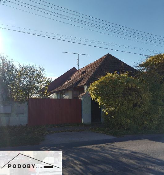 A family house in Veľké Úľany with a wooden gate and greenery in the surroundings.