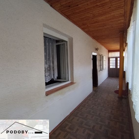 A hallway in a family house with a wooden decor floor and curtains on the windows.