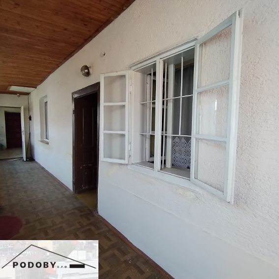 The veranda of a family house with a wooden ceiling and white plaster.