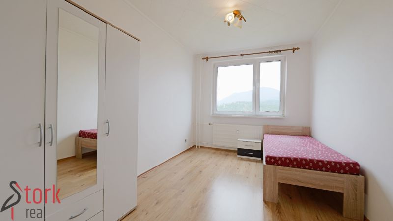 A bright room with a wardrobe and a bed, a floor with a wooden decor in a 3-room apartment.