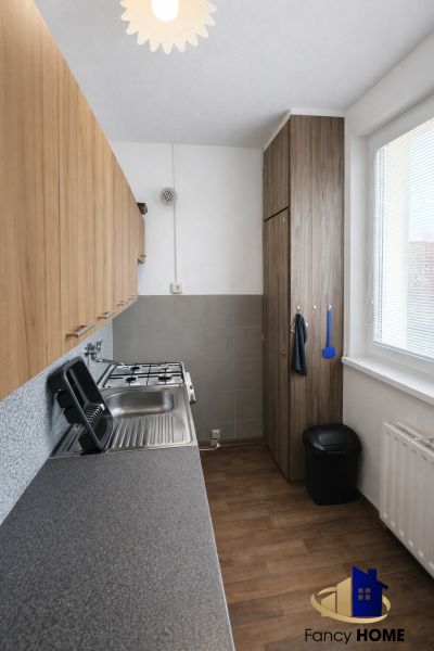 A kitchen in a 2-room apartment with a wooden decor floor and built-in furniture.