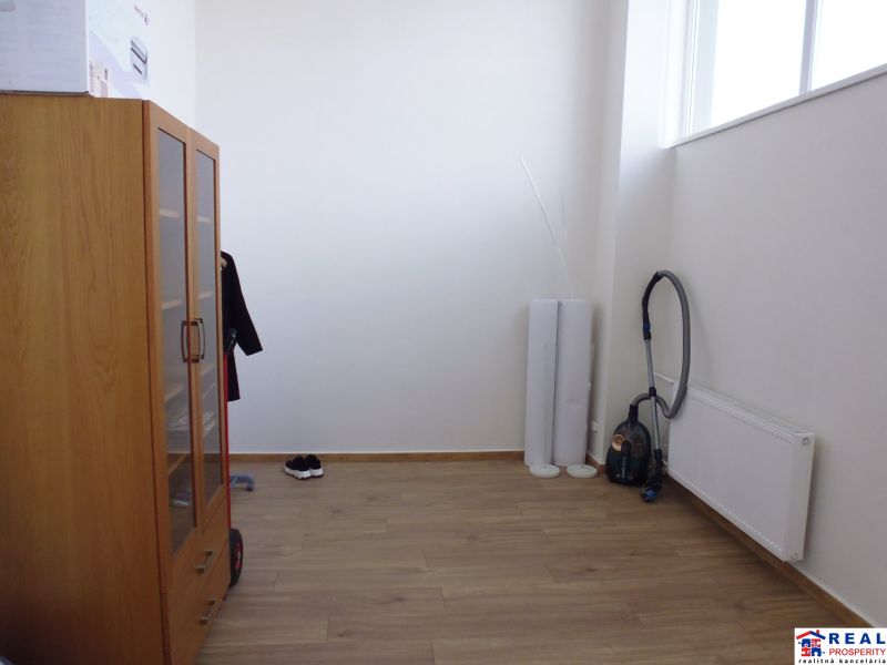 Commercial premises with a wooden decor floor, a cabinet, and a vacuum cleaner.
