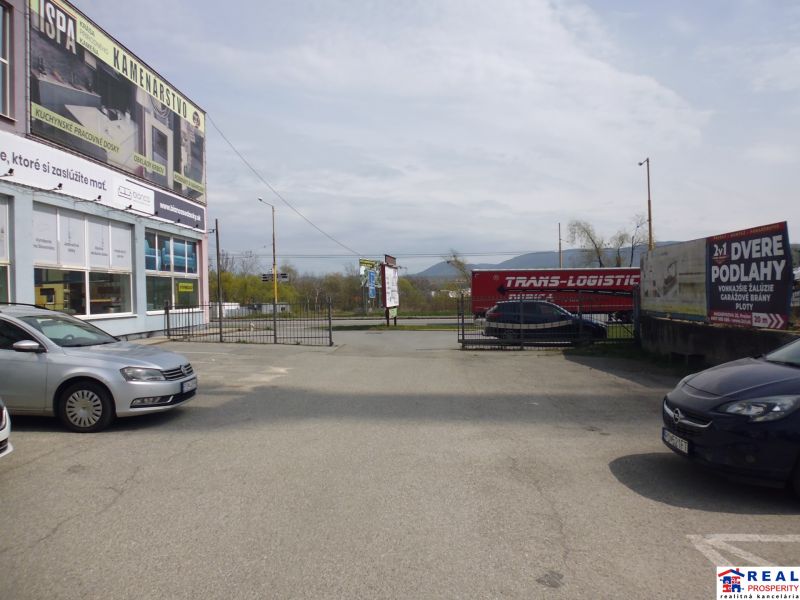 Parking lot at the commercial premises on Masarykova 22 in Prešov with cars and advertising signs.