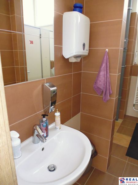 A sink with soap and a hand dryer in commercial premises.
