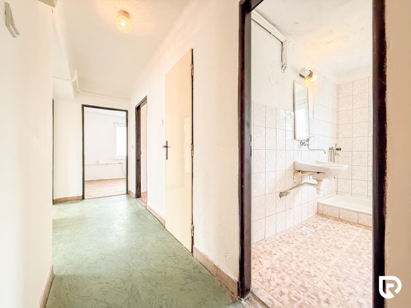 A hallway with a green floor, entrance to the bathroom and a room in a 3-room apartment.