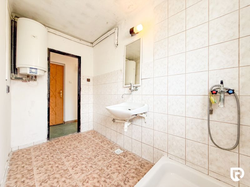 Bathroom with a sink, boiler, and light tiles in a 3-room apartment.