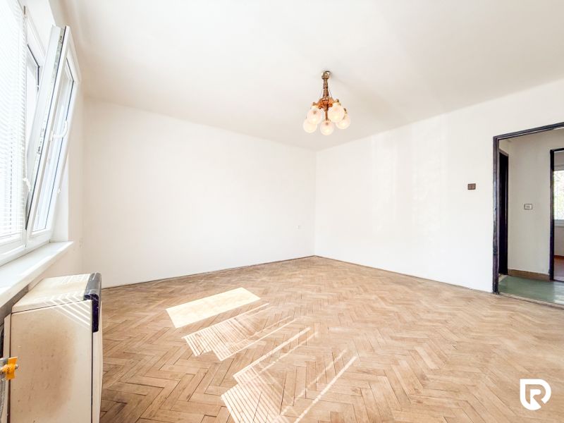 A spacious room with a window and a floor with a wooden decor in a 3-room apartment.
