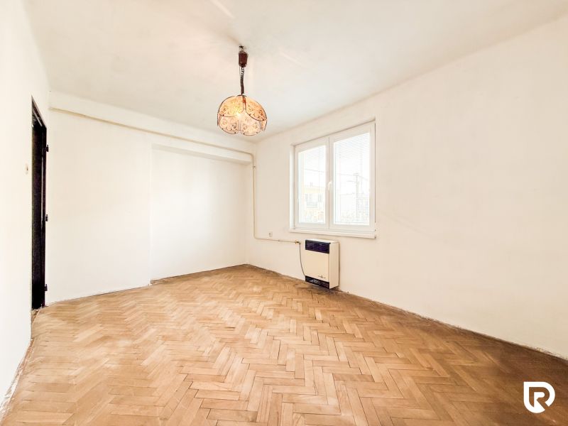 A room with a wooden decor floor and antique lighting in a 3-room apartment.