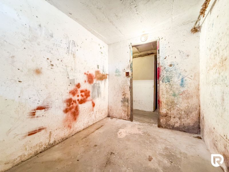 A white room with damaged walls and a long corridor in a 3-room apartment.