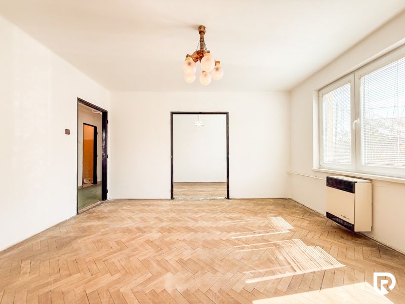 Living room with wood-patterned flooring in a 3-room apartment, large windows, glossy ceilings.