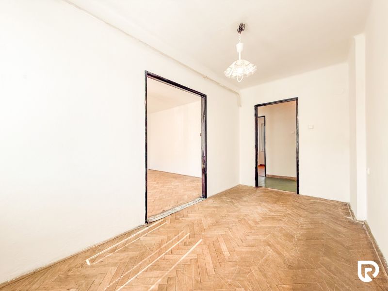 A room in a 3-room apartment with a wooden decor floor and white walls.