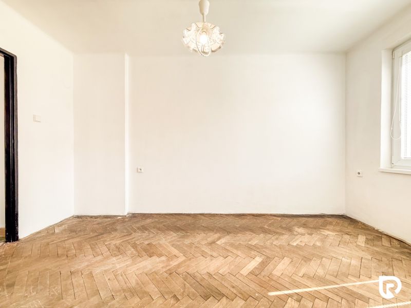 A room with a wooden decor floor and white walls in a 3-room apartment.