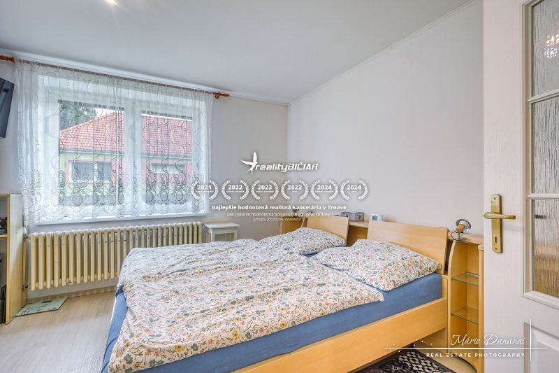 A bedroom in a family house with a large window and a double bed.