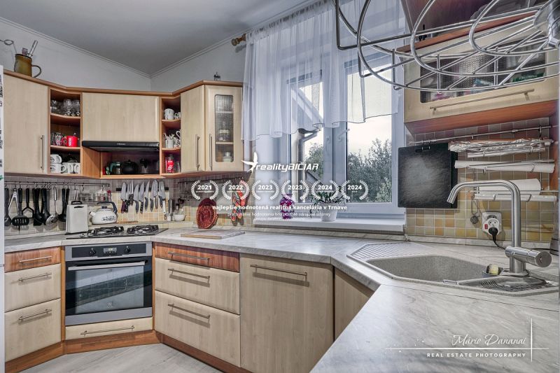 A kitchen in a family house with a kitchen unit, a stove, and a view through the window.