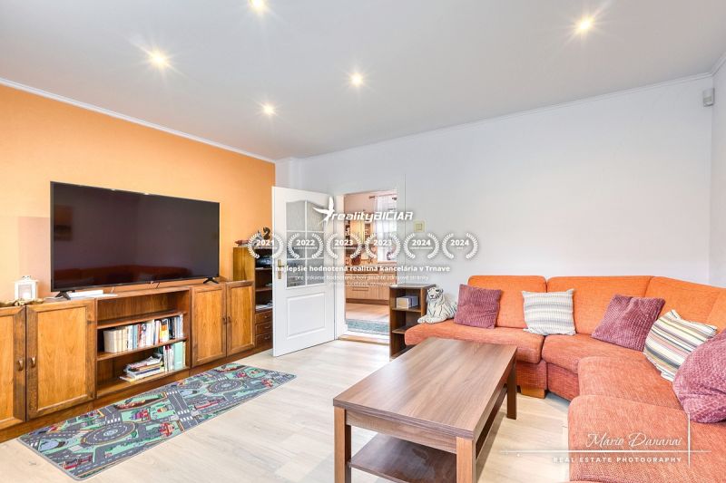 Living room in a family house with an orange sofa and a wooden decor floor.