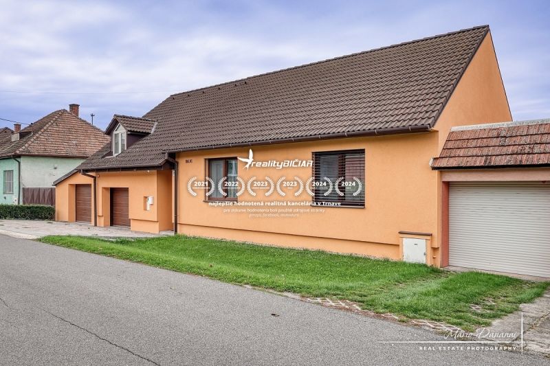 A family house on a street in Špačince with a gable roof and an orange facade.
