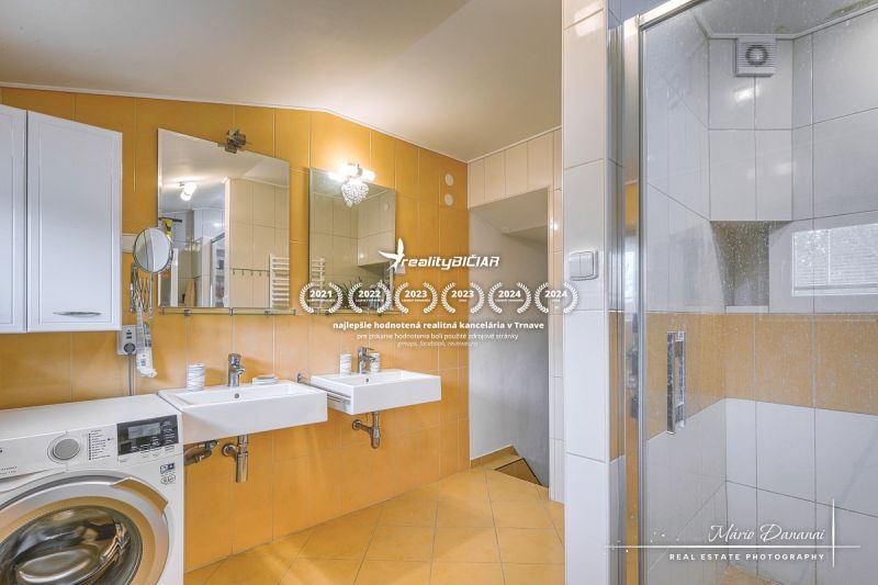 A bathroom in a family house with a double sink, shower, and washing machine.