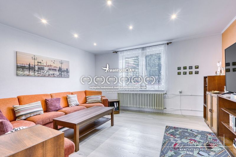 Living room in a family house with an orange sofa and wood-patterned flooring.