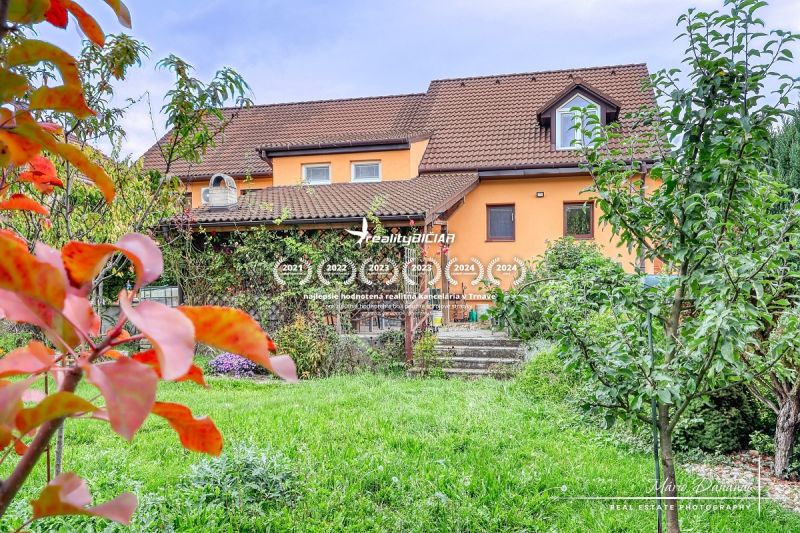 A family house in Špačince on Špačinská Street with a landscaped garden and an orange facade.