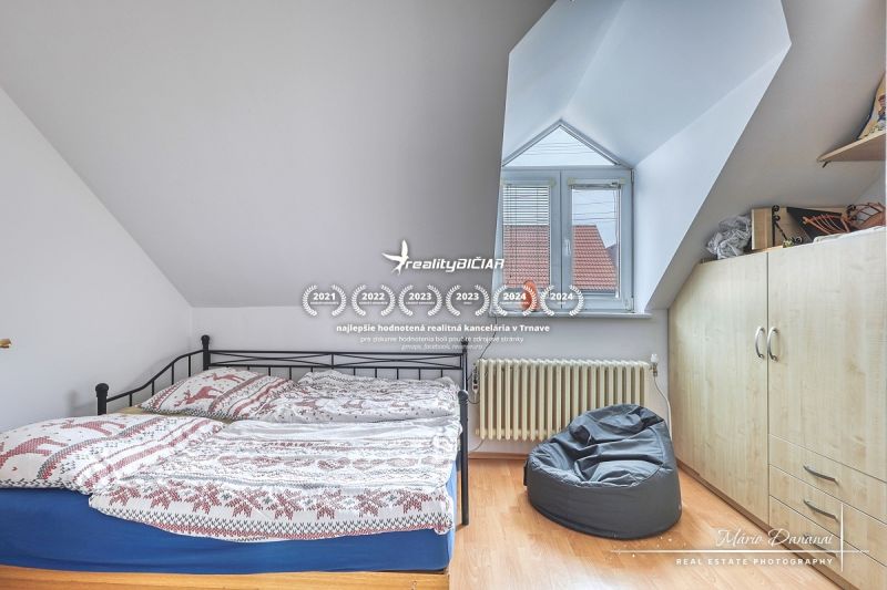 Bedroom in a family house with a bed, a pocket chair, and a floor with a wooden decor.