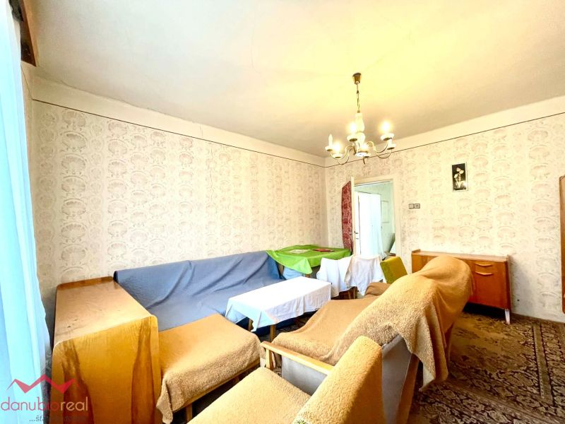 A living room in a family house with furniture covered with fabrics and patterned wallpaper.