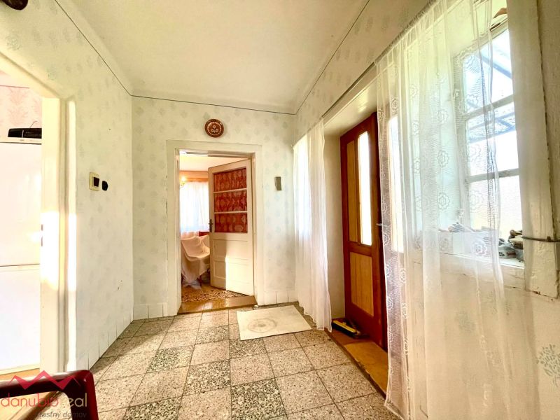 A hallway in a family house with a mosaic floor and light-colored walls.