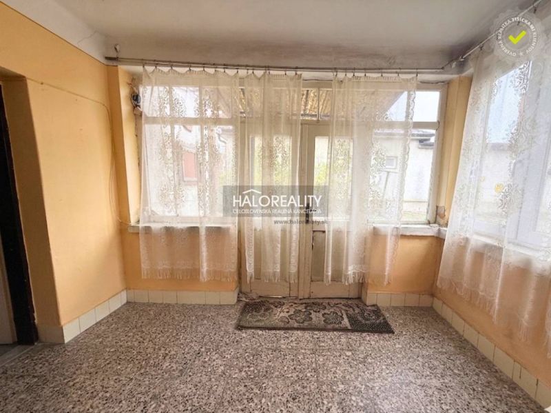 A family house with windows with lace curtains and a stone floor.