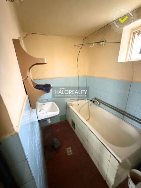 A bathroom in a family house with a bathtub, a sink, and light blue ceramic tiles.