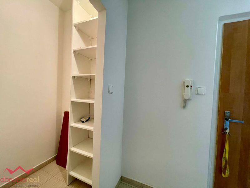 The 1-room apartment features built-in shelves and a door with an intercom.
