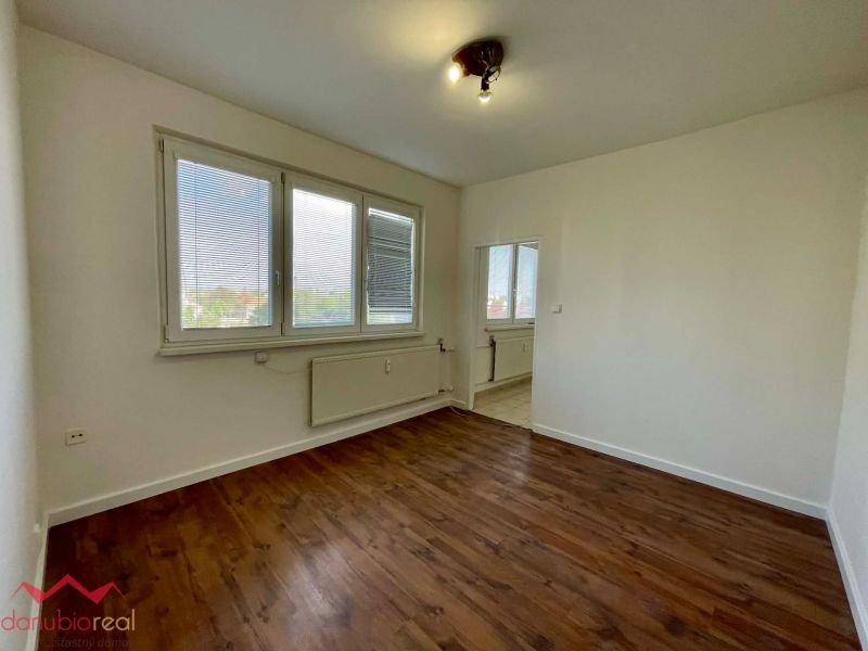 A one-room apartment with white walls and a floor with a wood decor.