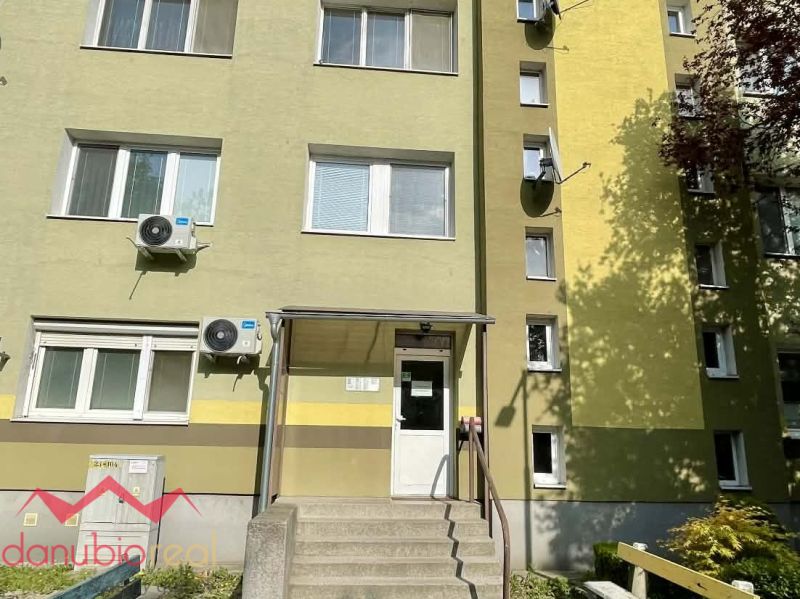 Entrance to an apartment building in Komárno, with a staircase and air conditioning units on the facade.