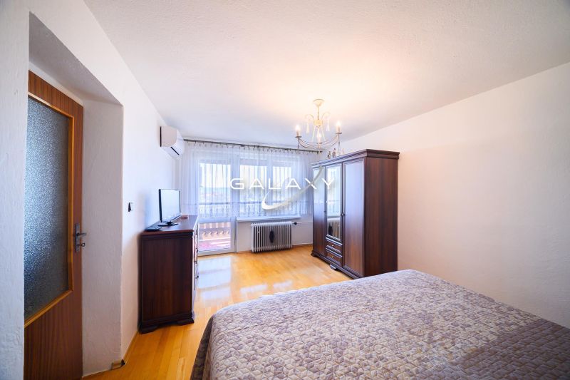 Bedroom in a family house with wood-patterned flooring, wardrobes, and a television.