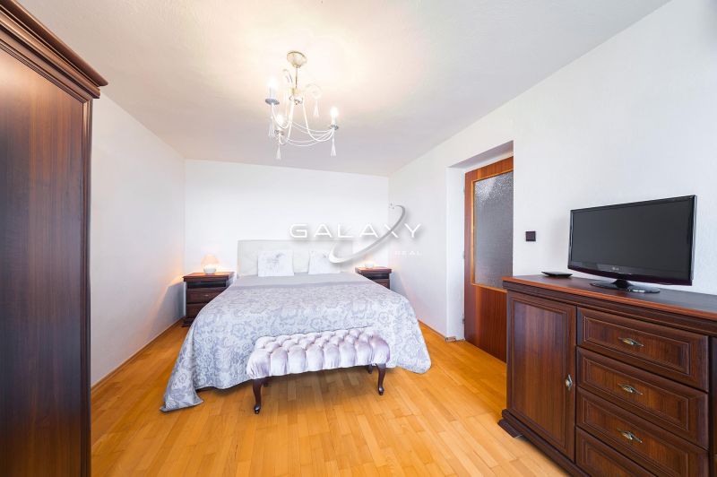 A bedroom in a family house with a bed, wardrobe, dresser, and floor with a wooden decor.