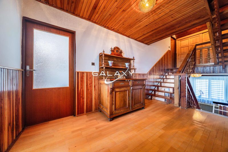 Family house with wood-decor flooring and wooden wall paneling, rustic furniture.
