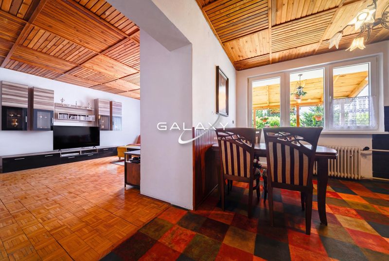 Interior of a family house with a dining room, living room, and wooden decor flooring.