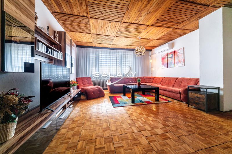 Living room in a family house with a wooden decor floor and an extensive sofa.