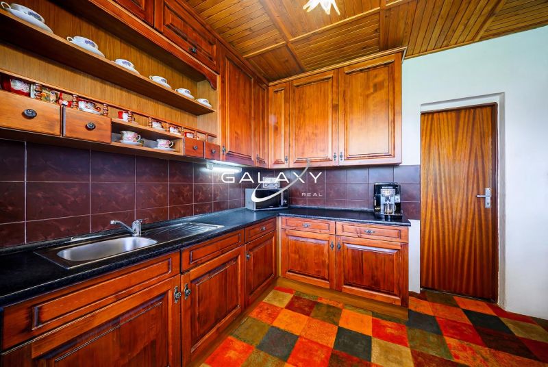 A kitchen in a family house with wooden decor and a black countertop.