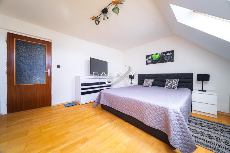 A bedroom with a bed and a wooden decor floor in a family house.