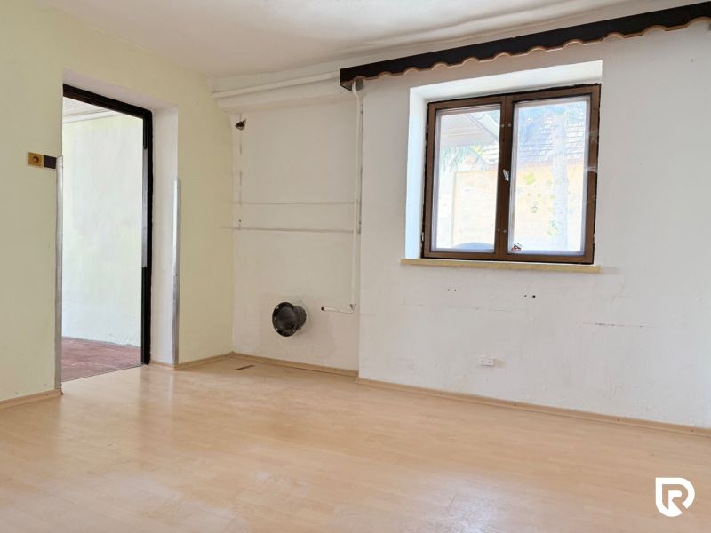 A room with a wooden floor decor, sunlight through the window, empty walls.