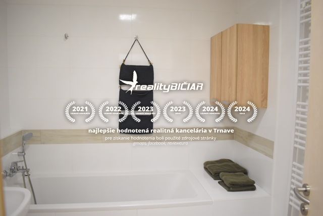 Bathroom of a 2-room apartment with a bathtub and white tiles, complemented by wooden cabinets.