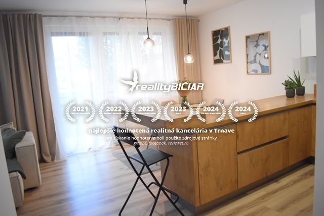 Living area in a 2-room apartment with wood-patterned flooring and large windows.