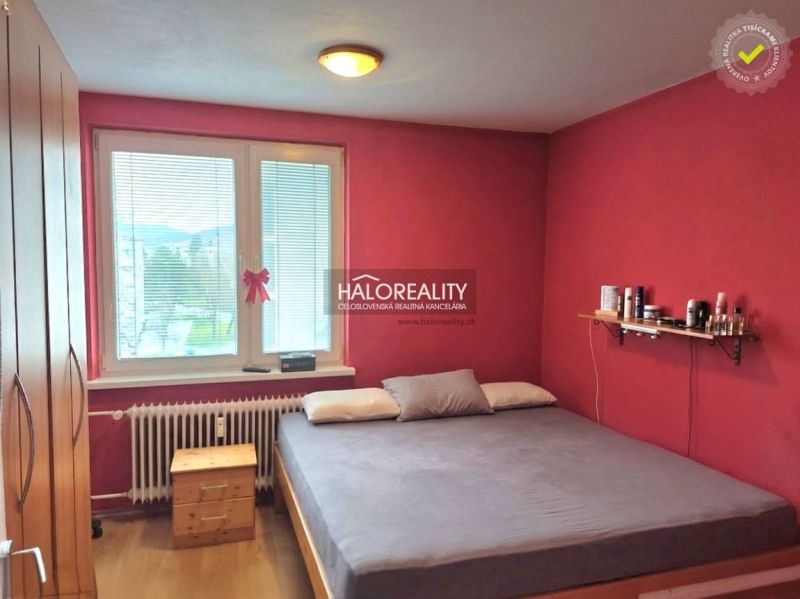 A bedroom in a 3-room apartment with red walls and a wooden decor floor.