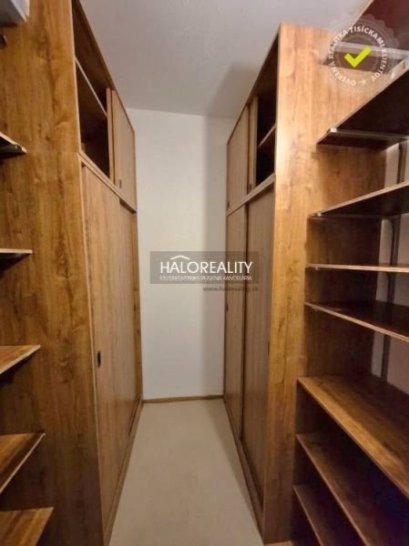 A wardrobe in a 3-room apartment with a wooden decor of cabinets and shelving system.