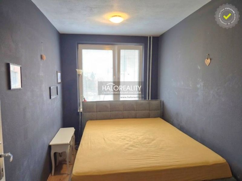 A bedroom in a 3-room apartment with black walls, a large window, and simple furniture.