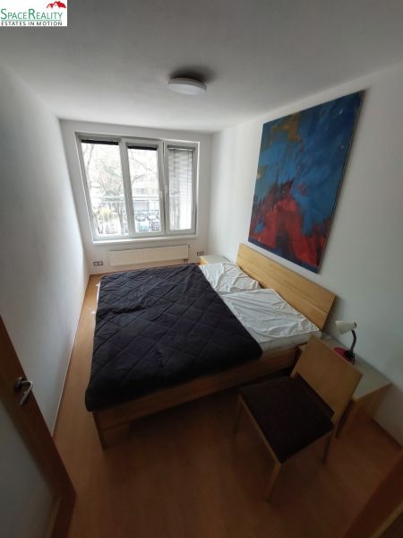 Bedroom in a 2-room apartment with a picture above the bed and a floor with a wooden decor.