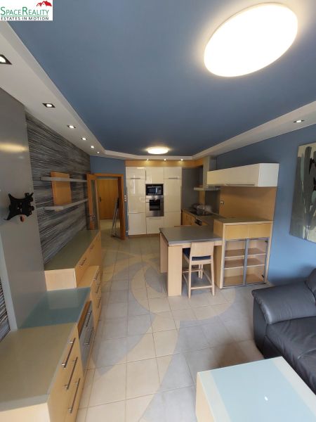 A kitchen in a 2-room apartment with light furniture and a blue ceiling.