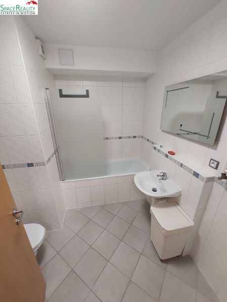 A bathroom with a bathtub, sink, and toilet in a 2-room apartment.