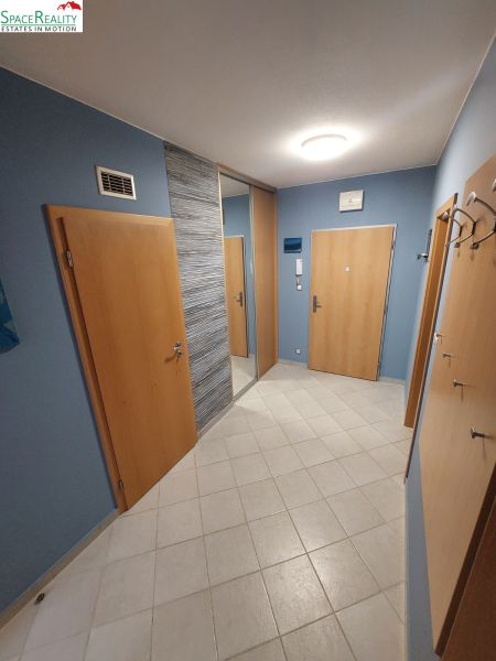 A blue hallway with tiles and wooden doors in a 2-room apartment.
