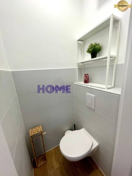 A bathroom with a wooden decor floor and white tiles in a 3-room apartment.